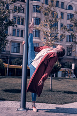 Great skills. Skilled professional ballerina developing her flexibility while standing near the lantern in the park © Viacheslav Yakobchuk