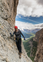 young pretty female mountain climber on a Via Ferrata in the Dolomites in Alta Badia
