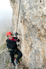 young attractive female mountain climber on a steep and exposed Via Ferrata in Alta Badia in the...