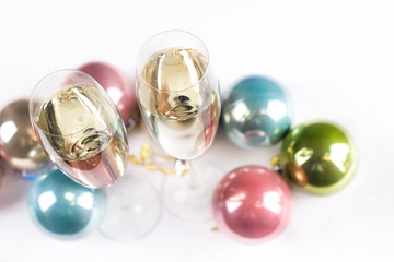 Two champagne glass with pastel color christmas toys on white background.