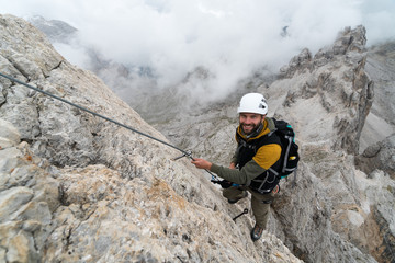 young male climber on a steep and exposed rock face climbing a Via Ferrata