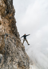 young male climber on a steep and exposed rock face climbing a Via Ferrata