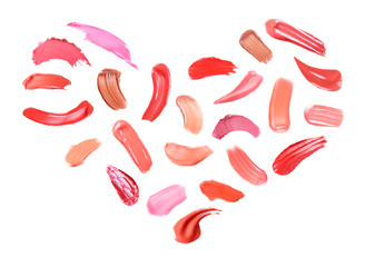 Creative set with different makeup product smears in shape of heart on white background