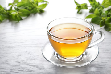 Cup with hot aromatic mint tea on table