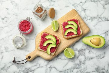 Tasty crisp toasts with avocado and chrain on wooden board, top view