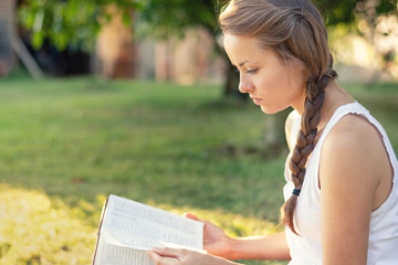 Christian worship and praise. A young woman is reading the bible in the early morning with sun in...