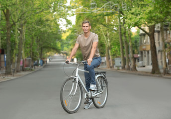Handsome man riding bicycle outdoors on summer day