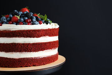 Stand with delicious homemade red velvet cake and space for text on black background