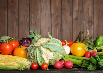 Assortment of fresh vegetables on table against wooden background. Space for text