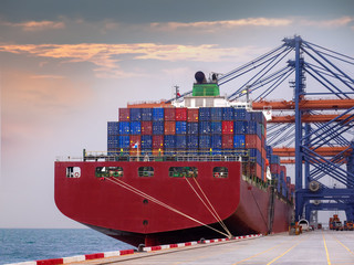 Naklejka premium The container vessel during discharging at an industrial port and move containers to container yard by trucks.