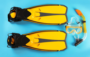 Pair of yellow flippers and diving mask on color background, top view