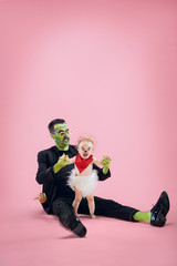 Halloween Family. Happy Father and Children Newborn Girl in Halloween Costume and Makeup. Bloody theme: the crazy maniak on pink studio background