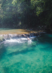 Fototapeta premium Semuc Champey, Guatemala - September 20 2018: Millennial young male traveler dives head-first into the crystal clear turquoise waters of Semuc Champey in Guatemala