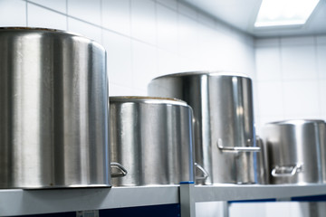 row of large metal cooking pots in an industrial size restaurant kithcen on a metal shelf