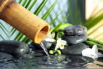 Fototapeta premium Traditional bamboo fountain with spa stones and flowers, closeup. Space for text