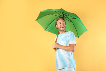 Man with green umbrella on color background © New Africa