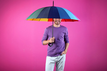 Man with rainbow umbrella on color background © New Africa