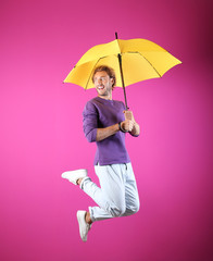 Man with yellow umbrella near color wall