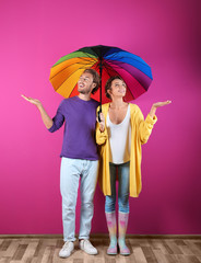 Couple with rainbow umbrella near color wall