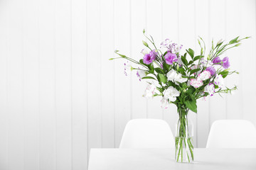 Glass vase with bouquet of beautiful flowers on table in room. Space for text