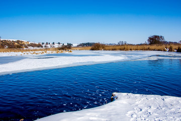 Winter landscape: the river on a sunny day, the banks of the river, covered with snow_