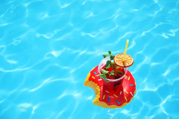 Inflatable drink holder with cocktail in swimming pool on sunny day. Space for text