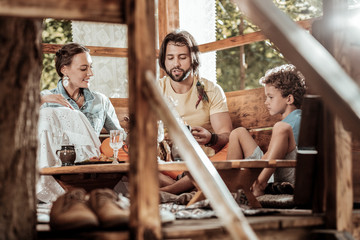 Obraz na płótnie Canvas Fresh air. Sweet pretty family of hippies having lunch at garden house having fun together
