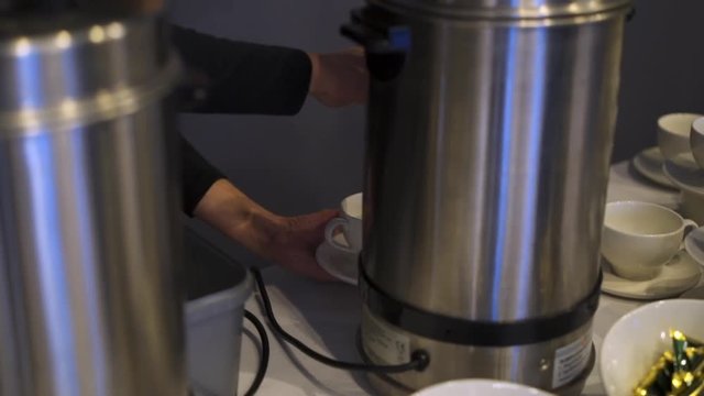 Man pour hot water from Electric hot water boiler to cup for make hot coffee or tea. Guests at buffet