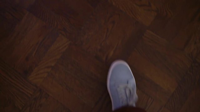 POV of person. Point of view of man walking indoors on wooden floor in blue sport casual shoes. 90 degree angle of person going legs