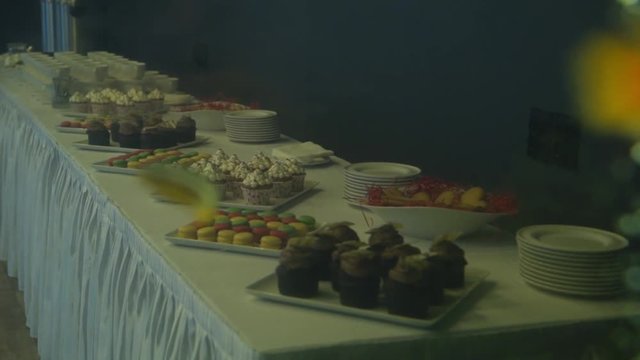 Golden fish in a freshwater aquarium slowmotion, cupcakes and desserts at background
