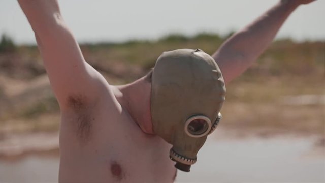 The guy wears a mask and shorts running around a muddy puddle