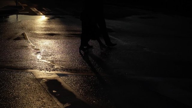 Man and young woman walking on a street. Couple holding hands on their date in a city street at early morning, shadows on a ground slowmotion silhouette