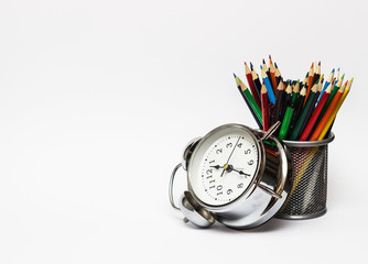 Alarm clock, colored pencils in a metal glass. The concept of time, and the business concept.