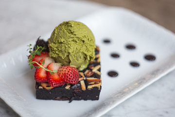 green tea ice cream on top of brownie with strawberry and almond