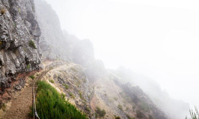 Hiking trail in between clouds. Pico do Arieiro, at 1,818 m high, is Madeira Island's third highest peak. Stone hiking path high up on the mountain to Pico Ruivo.