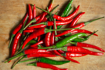 Group of fresh red and green chillies on chopping board