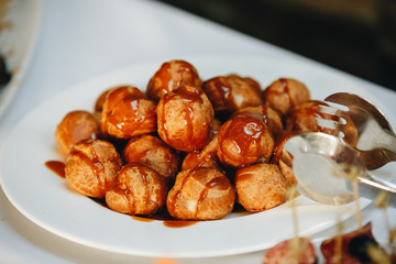 Profiterole or eclair. Profiterole olso known as eclair in little plate on the wooden table. Homemade profiterole filled with clotted cream for eclairs. Heap Cake profiteroles