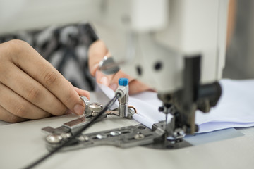 seamstress on a sewing machine makes a shirt in the sewing workshop. the woman on the machine sews the collar and cuffs