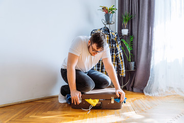 man need help to close suitcase. overloaded bag with clothes. travel concept