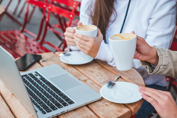 woman drinking coffee at outdoors cafe. laptop in table in cafe