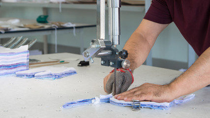 tailor with electric knife cut outs parts for sewing. industrial electric cloth cutting machine