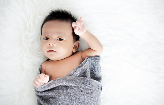 Adorable cute newborn baby in grey wrap diaper on a warm sheepskin. Family, new life, childhood, beginning concept.