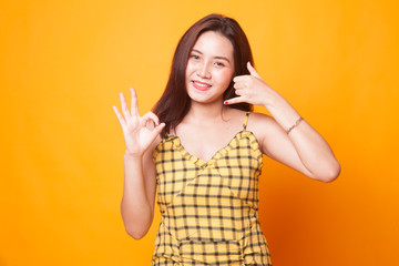 Young Asian woman show with phone gesture and OK sign.