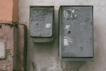Gray electrical boxes on the background of an old multi-colored wall