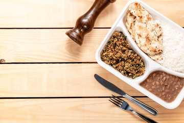 white rice chicken beans and manioc flour. Brazilian lunch box. top view