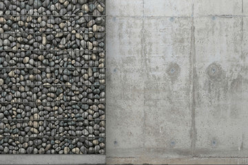 Background with gray concrete wall and gabion wall with stones in a metal grid frame. Front view with copy space. 3D rendering.