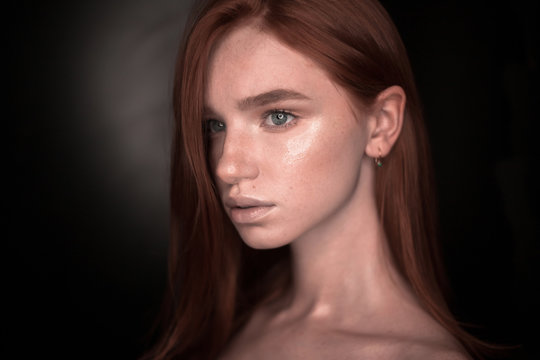 Beautiful serious redhead girl woman with healthy glow wet skin posing isolated over black wall background looking aside to empty copyspace.