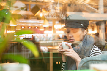 young woman in hat and scarf in a cafe
