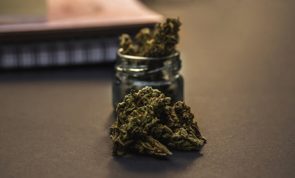 Cannabis buds, glass jar and notebooks with black background