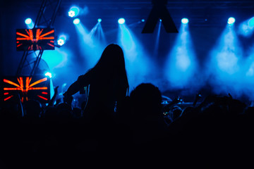 Silhouettes of concert crowd in front of bright stage lights